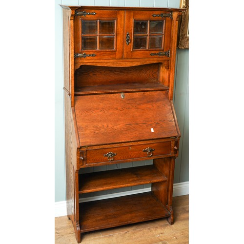 789 - An Arts & Crafts oak bureau bookcase, glazed upper section above slope front with fitted interior se... 