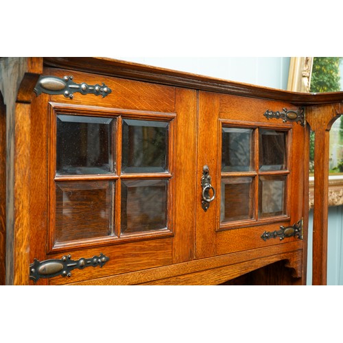 789 - An Arts & Crafts oak bureau bookcase, glazed upper section above slope front with fitted interior se... 