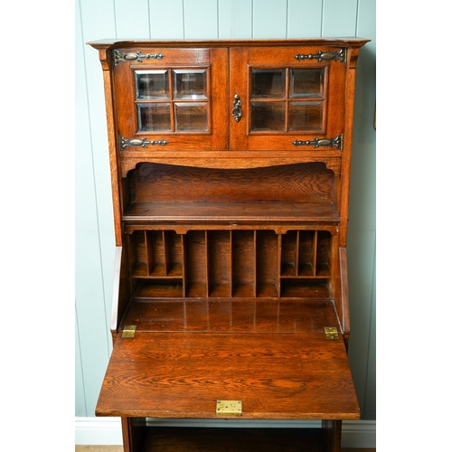 789 - An Arts & Crafts oak bureau bookcase, glazed upper section above slope front with fitted interior se... 