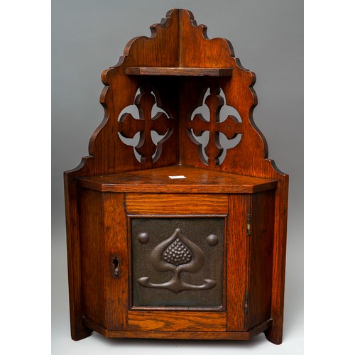 790 - An Arts & Crafts oak corner cabinet, the single door fitted copper panel embossed with a stylised ac... 