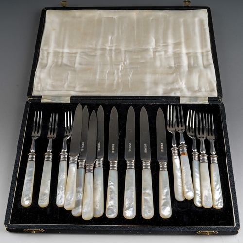 866 - A set of eight of George V silver mounted fruit knives and forks with mother-of-pearl handles, the t... 