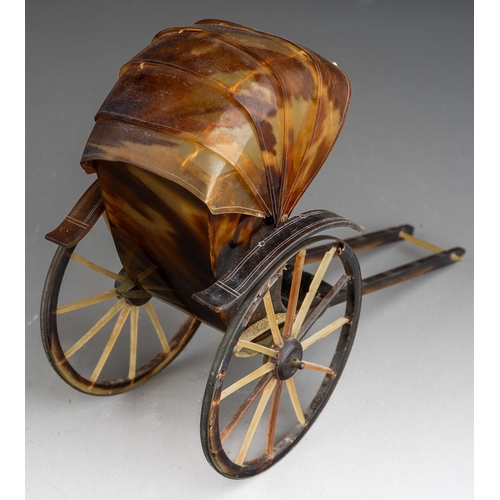 966 - A tortoiseshell and yellow metal mounted rickshaw, one wheel with damage,  height 10cm x length 14cm... 