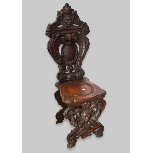 997 - A late 19th century walnut sgabello chair, the back ornately carved with lion masks and central scro... 