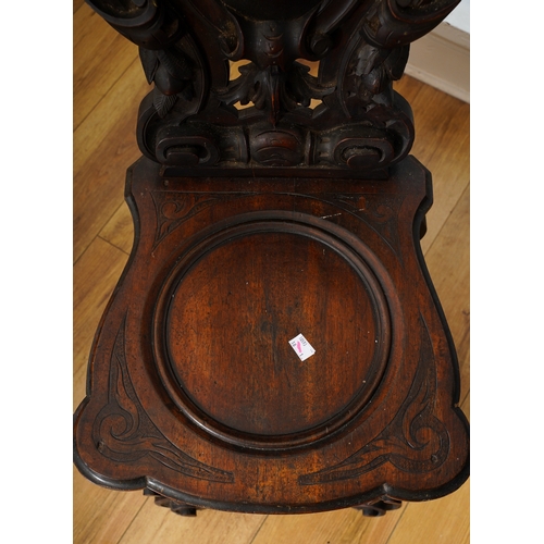 997 - A late 19th century walnut sgabello chair, the back ornately carved with lion masks and central scro... 