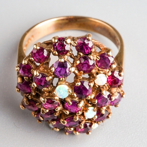 1007 - A 1970s 9ct gold ruby and opal dress ring. Deigned as an oval shape dome set throughout with rubies ... 