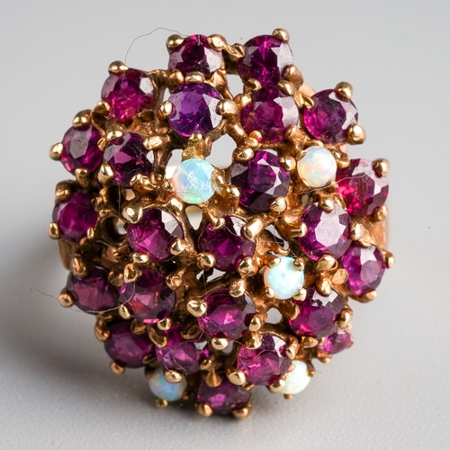 1007 - A 1970s 9ct gold ruby and opal dress ring. Deigned as an oval shape dome set throughout with rubies ... 