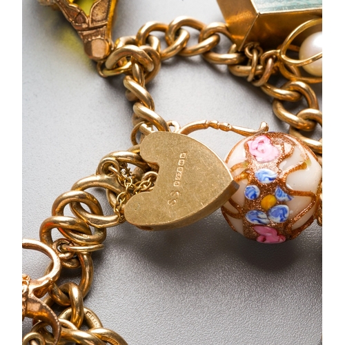 1011 - A gold charm bracelet. The solid curb link chain with scroll embossed padlock, suspending a series o... 