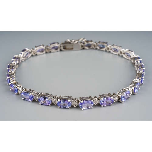 704 - A tanzanite and diamond line bracelet, the oval tanzanite's interspaced by round brilliant cut diamo... 