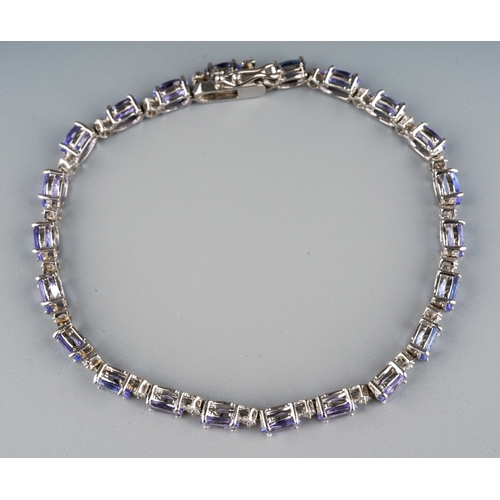 704 - A tanzanite and diamond line bracelet, the oval tanzanite's interspaced by round brilliant cut diamo... 