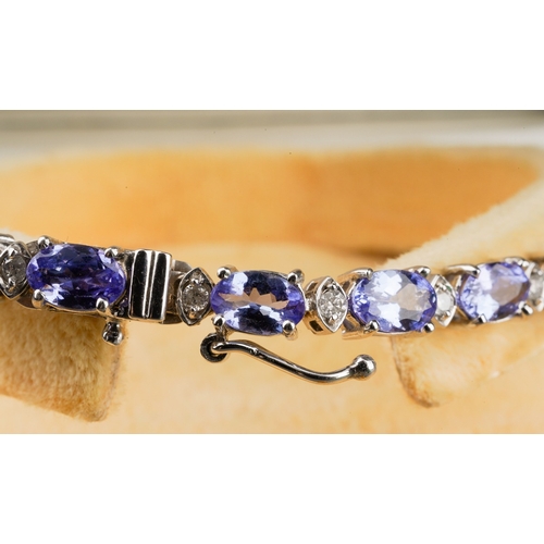 704 - A tanzanite and diamond line bracelet, the oval tanzanite's interspaced by round brilliant cut diamo... 