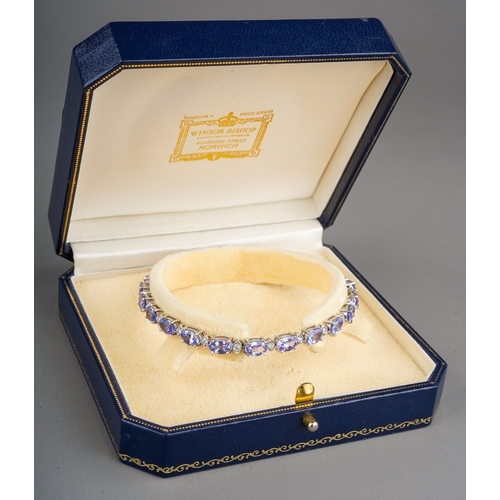 704 - A tanzanite and diamond line bracelet, the oval tanzanite's interspaced by round brilliant cut diamo... 