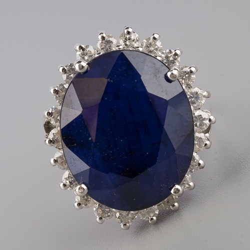 710 - A dress ring, set with an oval shape glass filled corundum, surrounded by round brilliant cut diamon... 