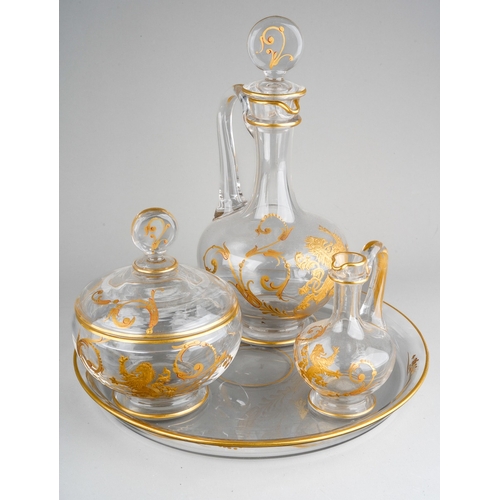 133 - An early 20th century Baccarat clear glass and gilt three piece decanter and jar set on circular tra... 