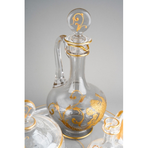 133 - An early 20th century Baccarat clear glass and gilt three piece decanter and jar set on circular tra... 