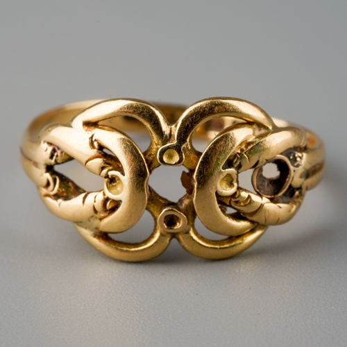 505 - An Edwardian 18ct gold ring, designed as a stylised knot, gemstone settings present but heavily worn... 