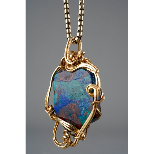 508 - A hardstone pendant with chain, the hardstone displaying green, blue and red colours, mounted within... 