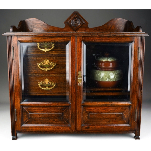 959 - An Edwardian oak smokers cabinet, raised back above bevel edge glazed double doors enclosing a shelf... 