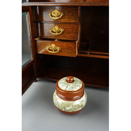 959 - An Edwardian oak smokers cabinet, raised back above bevel edge glazed double doors enclosing a shelf... 