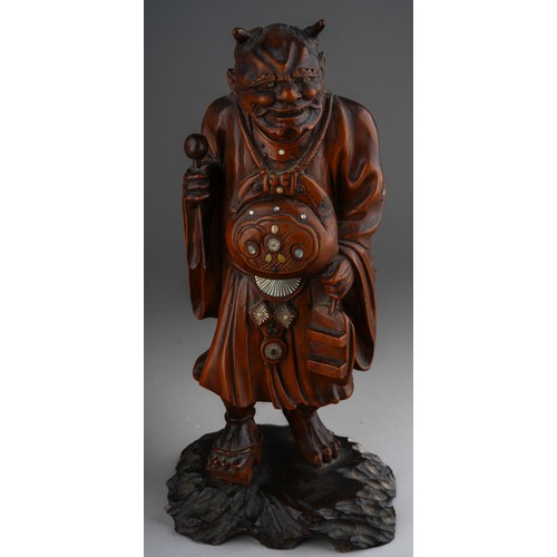 1003 - A Meiji period Japanese boxwood and inlaid okimono of a demon, carved as standing on an ebonised bas... 