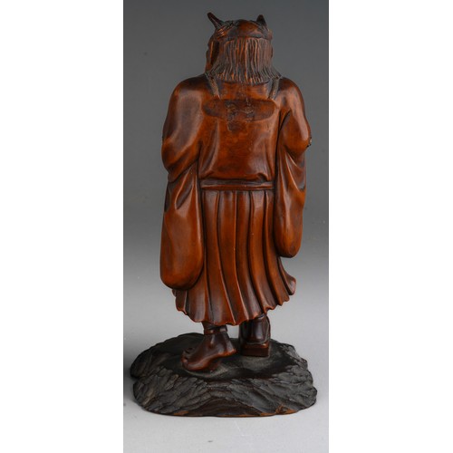 1003 - A Meiji period Japanese boxwood and inlaid okimono of a demon, carved as standing on an ebonised bas... 