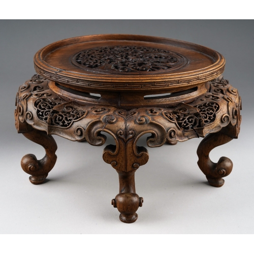 92 - A Chinese carved and pierced hardwood stand of circular form, the top with dragon with pearl amongst... 