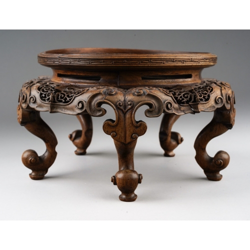 92 - A Chinese carved and pierced hardwood stand of circular form, the top with dragon with pearl amongst... 