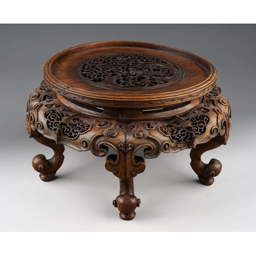 92 - A Chinese carved and pierced hardwood stand of circular form, the top with dragon with pearl amongst... 