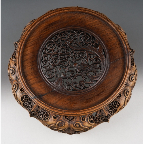 92 - A Chinese carved and pierced hardwood stand of circular form, the top with dragon with pearl amongst... 