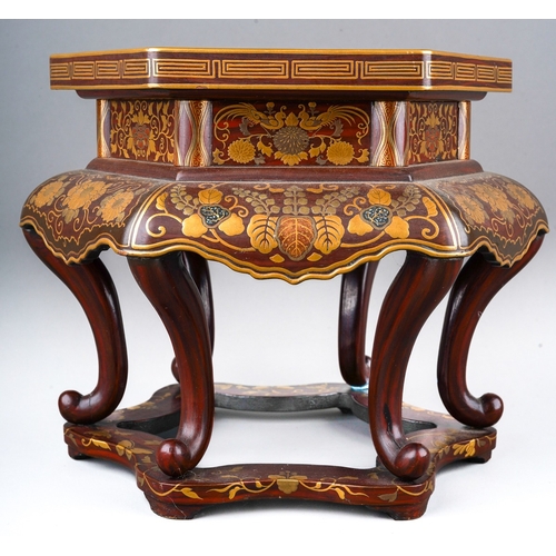 121 - A Japanese lacquered stand of hexagonal form decorated with Maki-e flowers and foliage, wavy apron, ... 