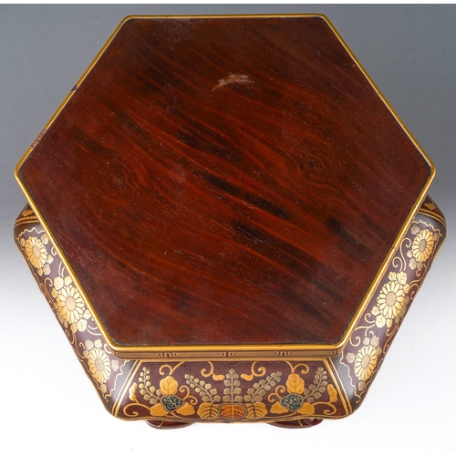 121 - A Japanese lacquered stand of hexagonal form decorated with Maki-e flowers and foliage, wavy apron, ... 