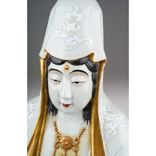 133 - A Japanese porcelain Satsuma figure of a seated Guanyin wearing a textured white robe and holding a ... 