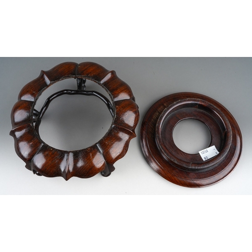 139 - A Chinese hardwood two piece stand, the turned circular top with short foot on a wavy lotus style ba... 