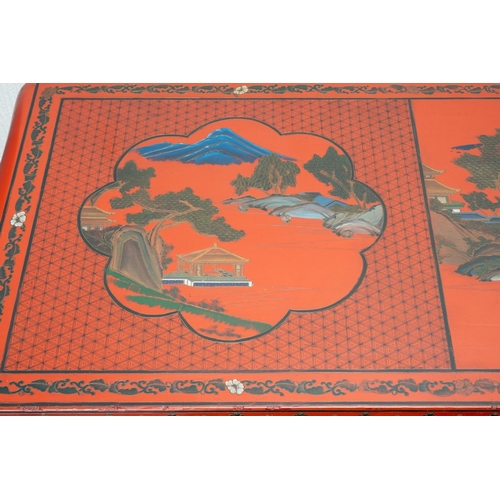141 - A Chinese red lacquer carved altar table with a pierced frieze, the top decorated with mountainous l... 