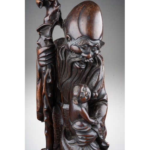 167 - A Chinese carved hardwood figure of a elder with a staff and holding a child , silver wire inlay, ca... 