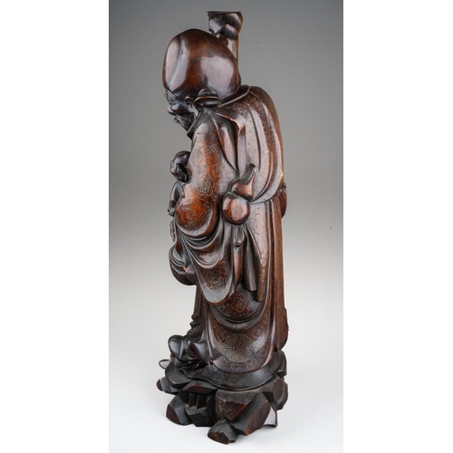 167 - A Chinese carved hardwood figure of a elder with a staff and holding a child , silver wire inlay, ca... 