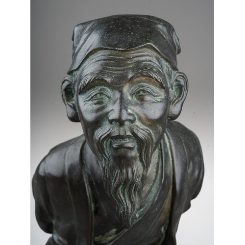 168 - A 20th century Japanese cast bronze figure of a man holding his hands behind his back, standing on a... 