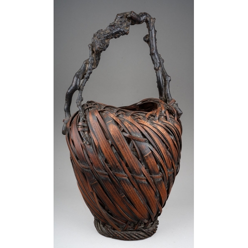 255 - A Japanese woven wicker Ikebana basket with root handle, the basket of oval form, height 44cm