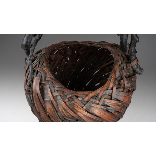 255 - A Japanese woven wicker Ikebana basket with root handle, the basket of oval form, height 44cm