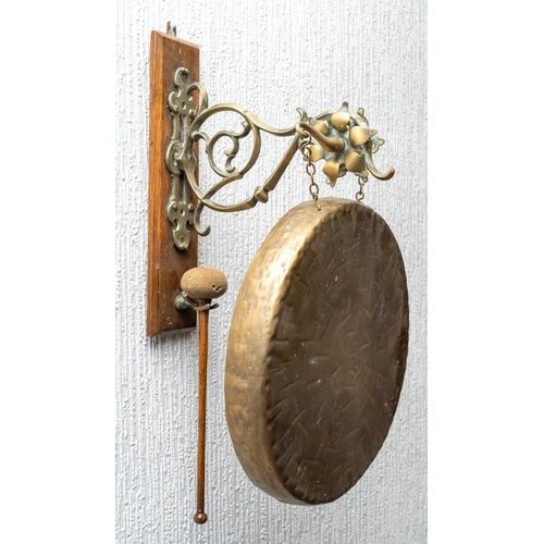 315 - A late Victorian wall hanging dinner gong, oak wall mount with gothic and foliate arm, 28cm diameter... 