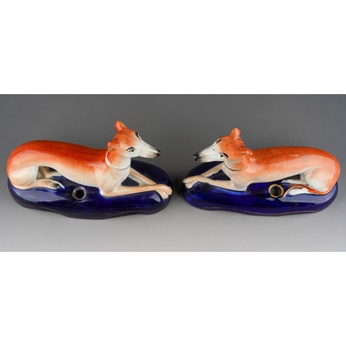 18 - A pair of 19th Century Staffordshire quill holders modelled as recumbent greyhounds on navy oval bas... 