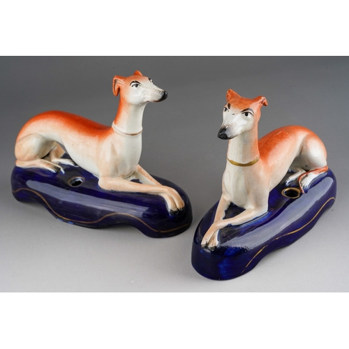 18 - A pair of 19th Century Staffordshire quill holders modelled as recumbent greyhounds on navy oval bas... 