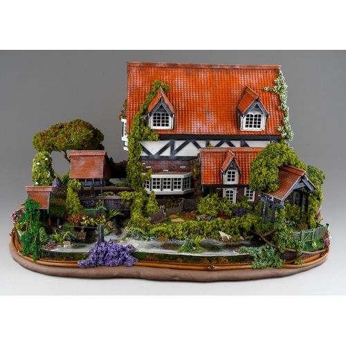 410 - A scale model diorama of a Tudor cottage with garden and streams in the style of Lilliput Lane, fitt... 