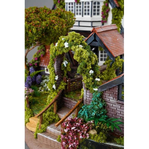 410 - A scale model diorama of a Tudor cottage with garden and streams in the style of Lilliput Lane, fitt... 