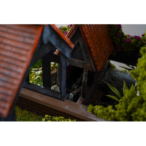 410 - A scale model diorama of a Tudor cottage with garden and streams in the style of Lilliput Lane, fitt... 