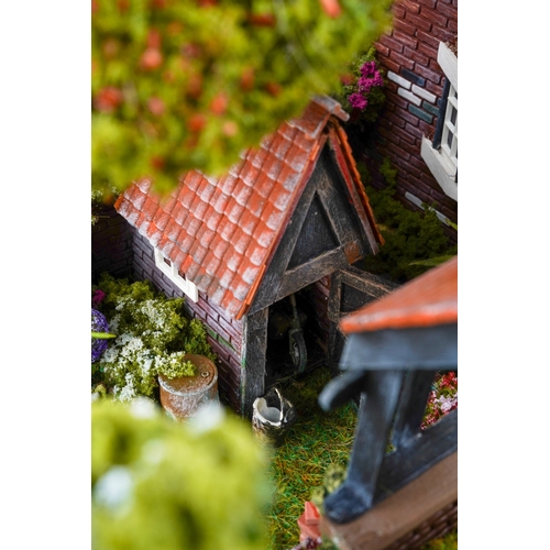 410 - A scale model diorama of a Tudor cottage with garden and streams in the style of Lilliput Lane, fitt... 