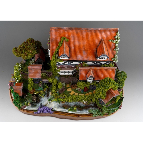 410 - A scale model diorama of a Tudor cottage with garden and streams in the style of Lilliput Lane, fitt... 