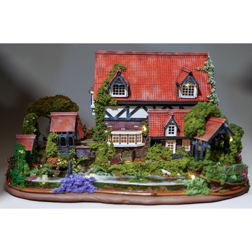 410 - A scale model diorama of a Tudor cottage with garden and streams in the style of Lilliput Lane, fitt... 