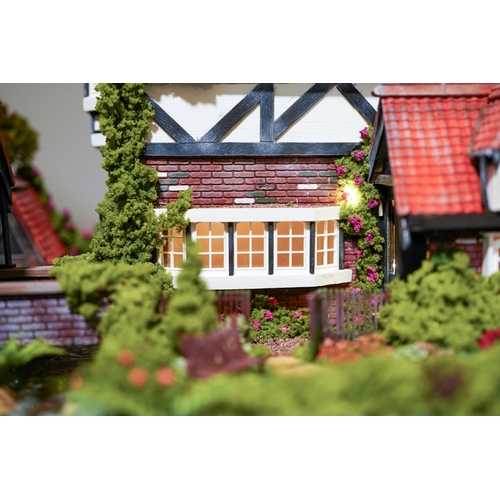 410 - A scale model diorama of a Tudor cottage with garden and streams in the style of Lilliput Lane, fitt... 