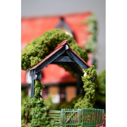 410 - A scale model diorama of a Tudor cottage with garden and streams in the style of Lilliput Lane, fitt... 