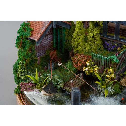 410 - A scale model diorama of a Tudor cottage with garden and streams in the style of Lilliput Lane, fitt... 